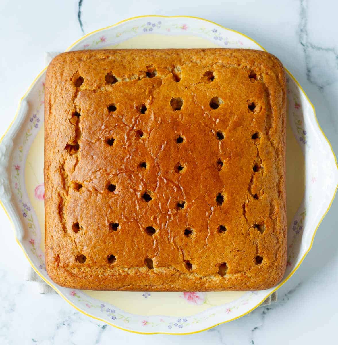 cake with holes poked all over on a cake platter.