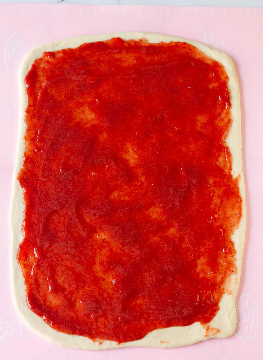 strawberry jam spread over the rolled out dough.