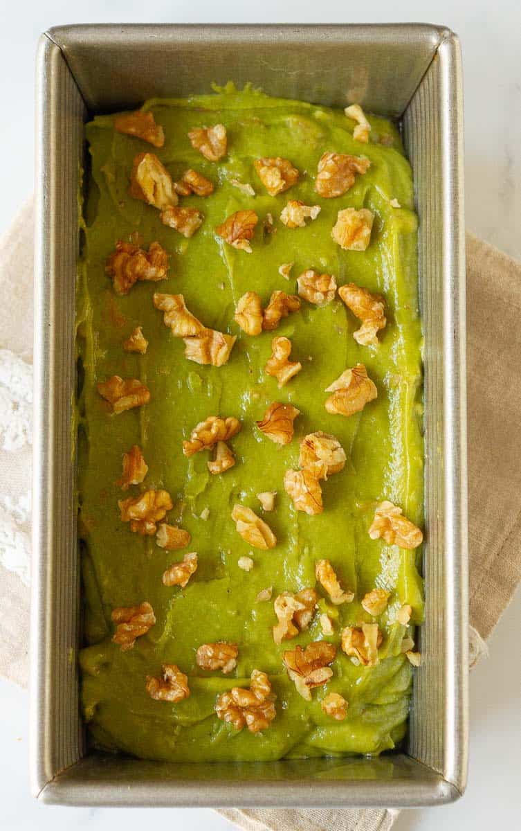 batter in the cake tin, topped with more walnuts