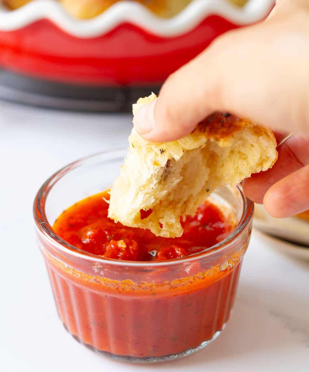 Dipping the pizza pull-apart bread in tomato sauce.