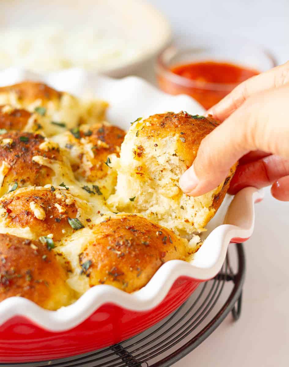 A hand pulling a piece of the pizza pull-apart bread.