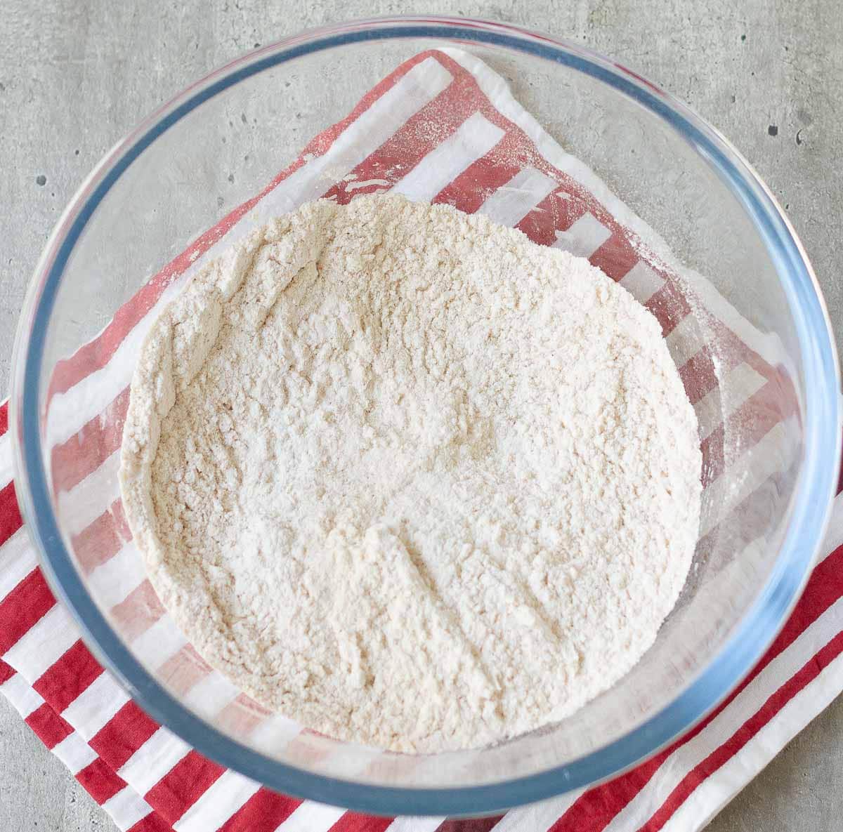 Dry ingredients for oatmeal cookies in a glass bowl.