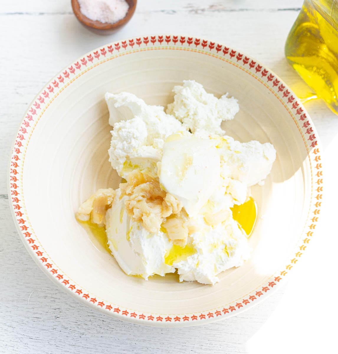 Cream cheese, goat cheese, roasted garlic, olive oil, and lemon juice in a bowl.