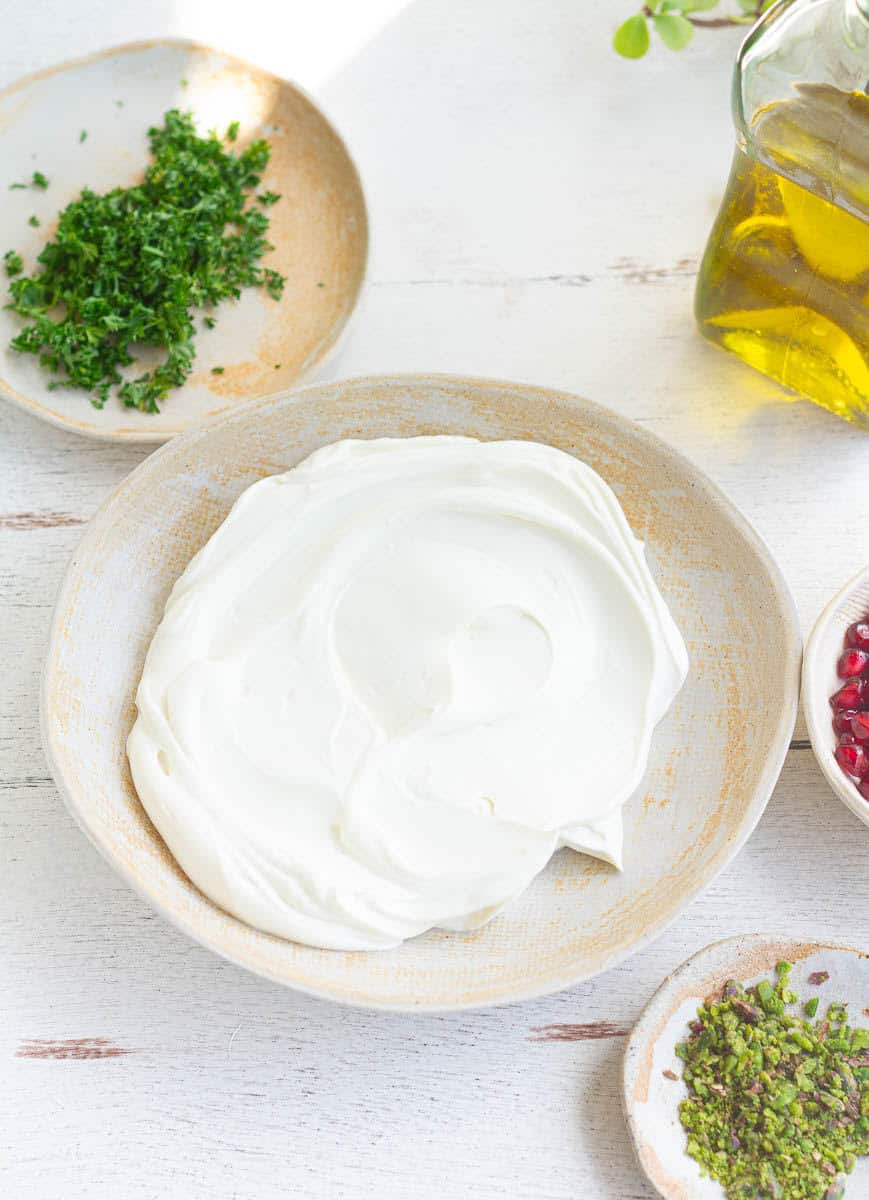 whipped creamy cheese in a bowl with toppings on the side.