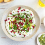 Creamy dip in a bowl garnished with parsley and pomegranate arils.