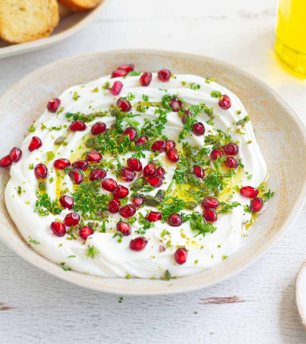 whipped goat cheese dip garnished with parsley and pomegranates in a bowl.