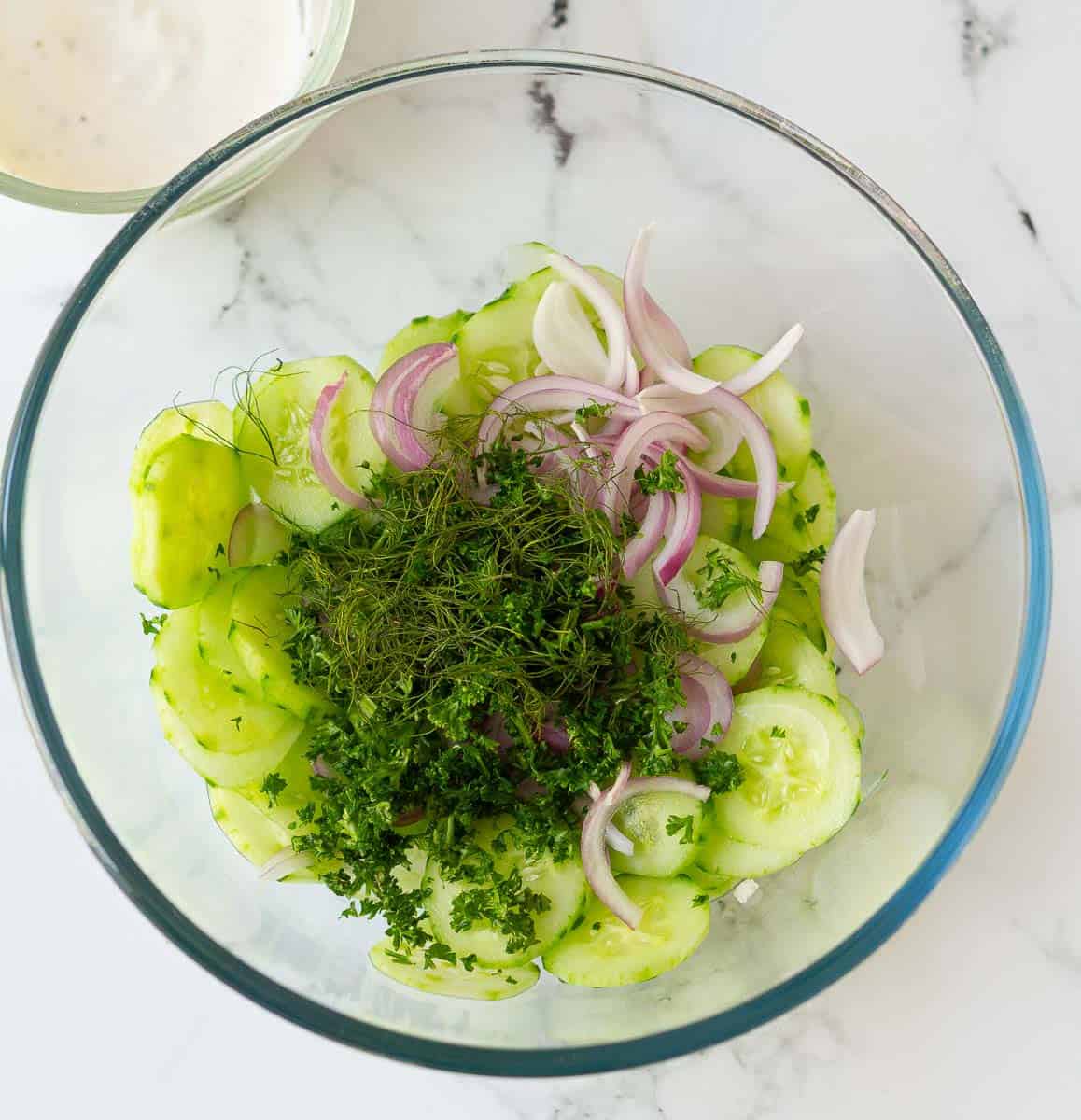cucumber, onion, parsley and dill in a large glass bowl
