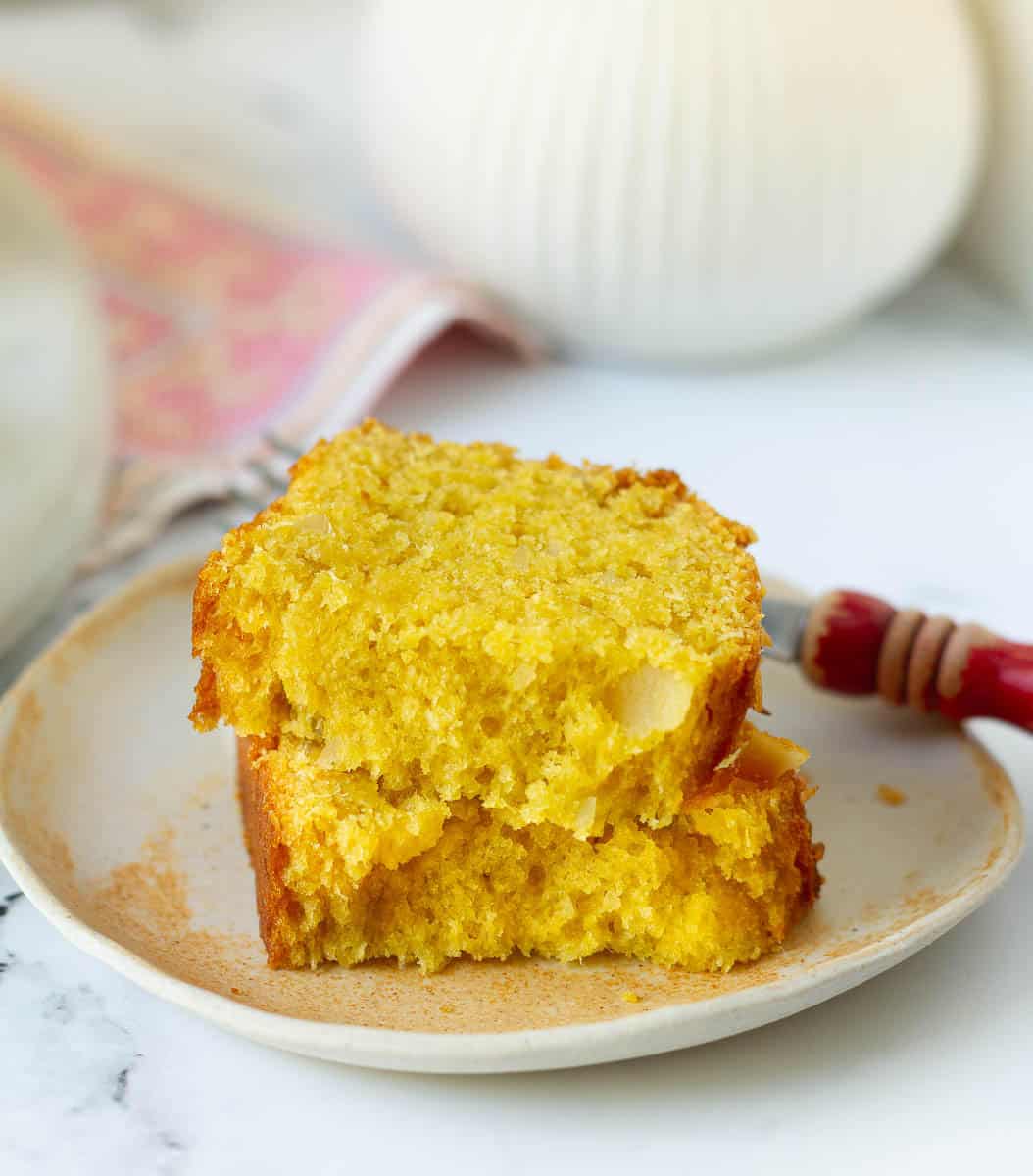 A slice of mango bread cut into half on a small plate.