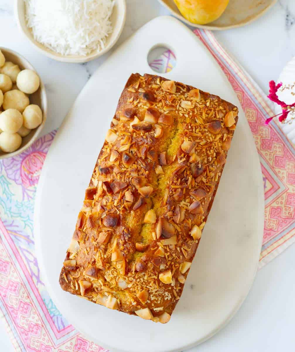 Mango bread on a white board with ingredients on the side.