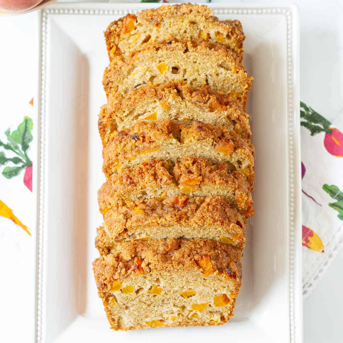 Sliced bread with peaches on a white rectangular platter.