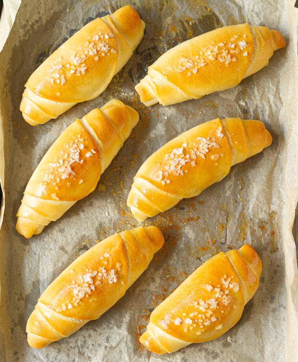 Baked salt bread rolls on parchment paper.