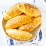 Rolls in a bowl on a blue and white kitchen towel.