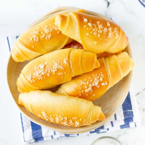 Rolls in a bowl on a blue and white kitchen towel.
