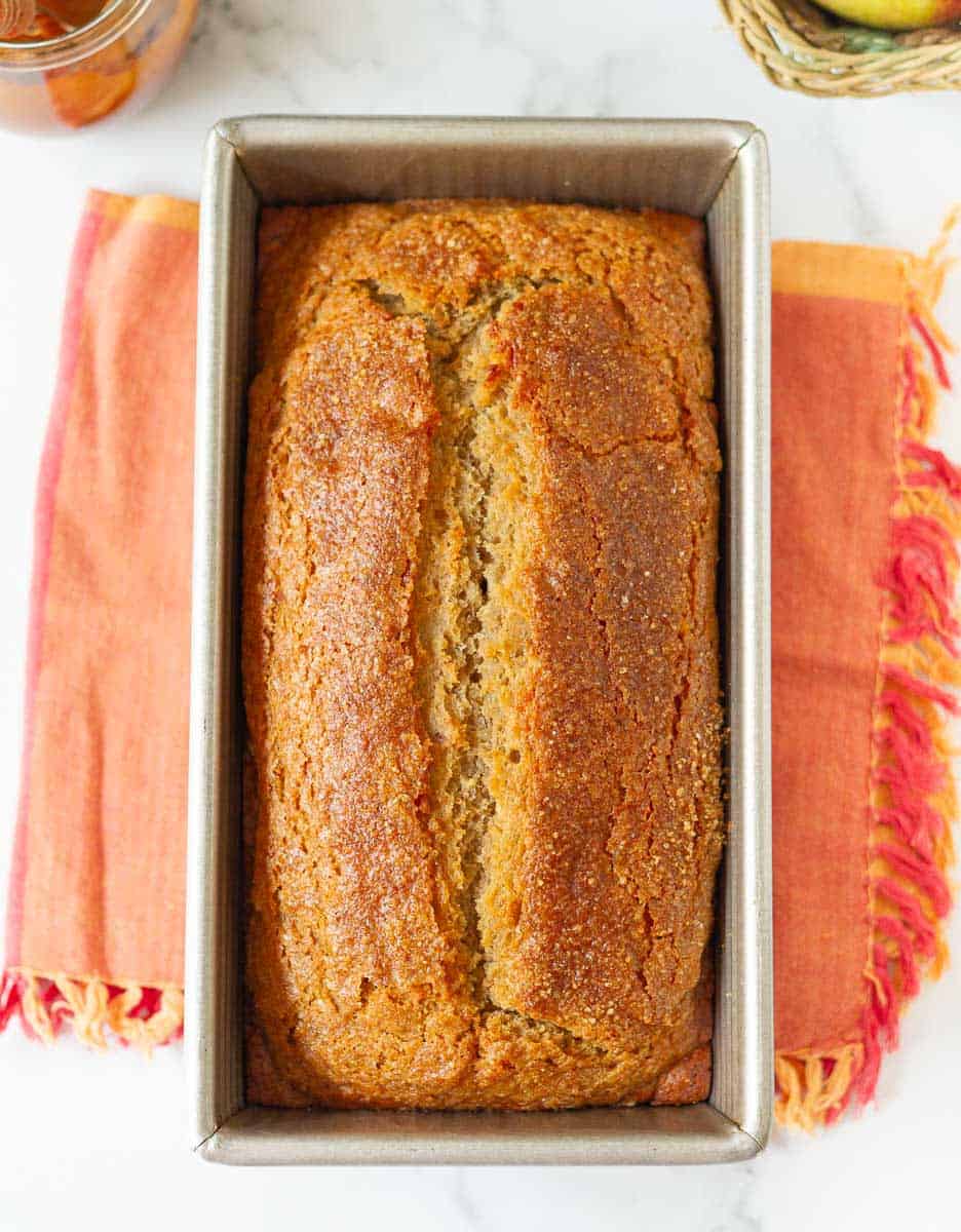 Baked Apple Butter Bread in a loaf pan on a red cloth napkin.