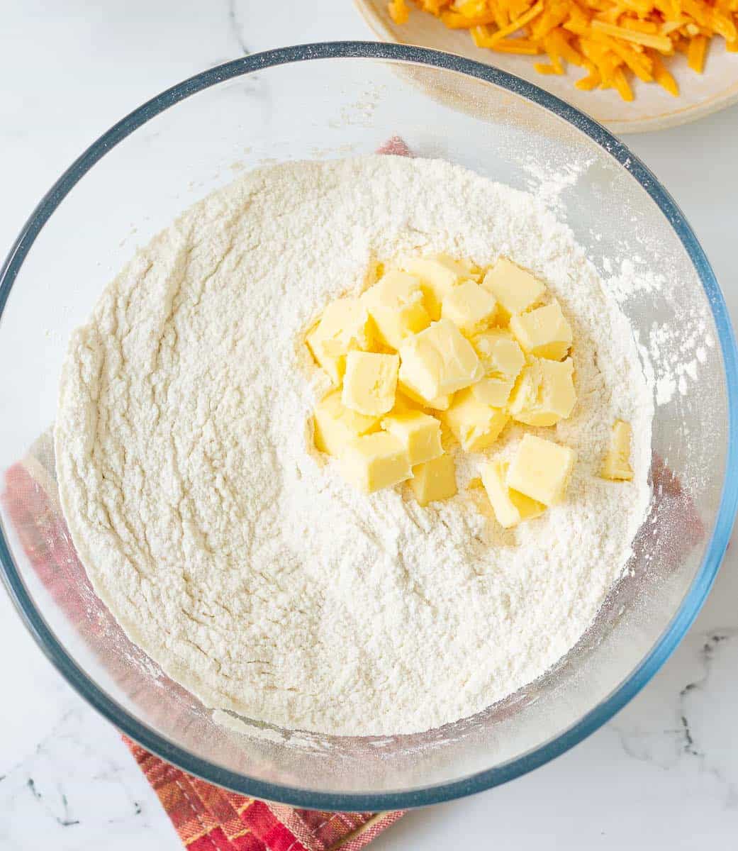 cubed butter and dry ingredients for cheddar cheese scones in a glass bowl