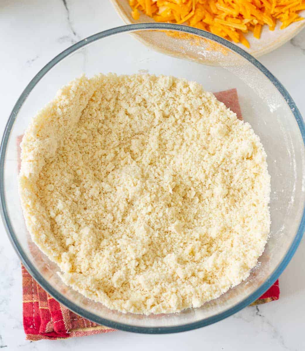 Butter and dry ingredients mixed together in a glass bowl for making cheese scones