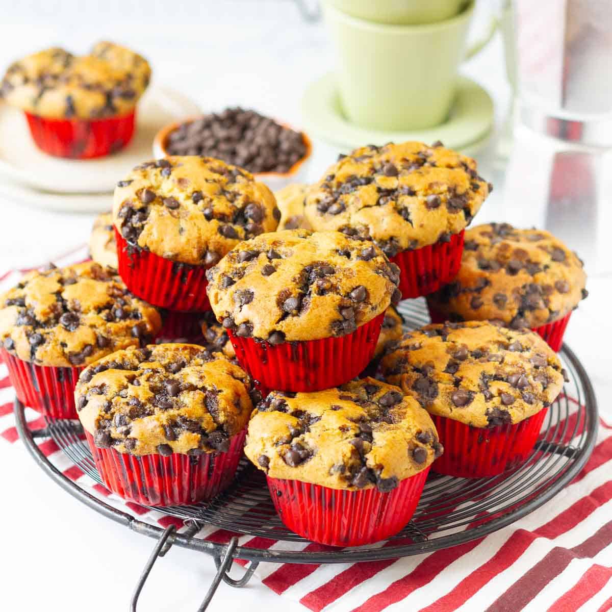 Chocolate chip muffins stacked on a round wire rack.