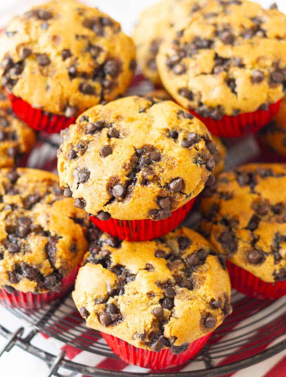 muffins with chocolate chips stacked on a wire rack.