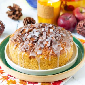 Cinnamon Swirl Apple Cake on a platter with candle and apples around.