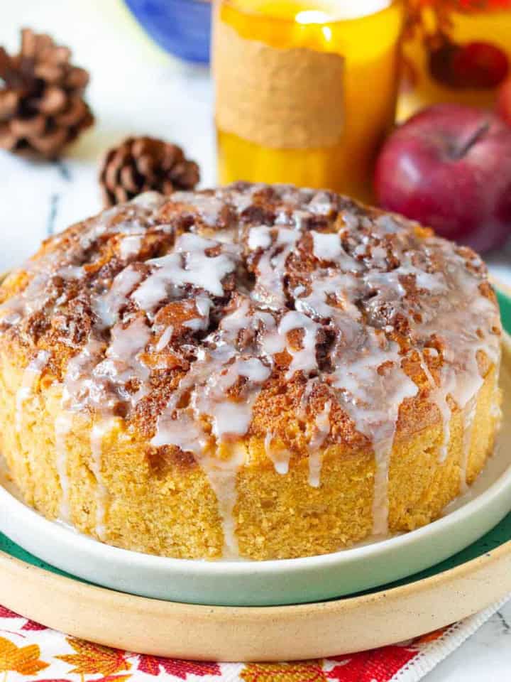 Cinnamon Swirl Apple Cake on a platter with candle and apples around.