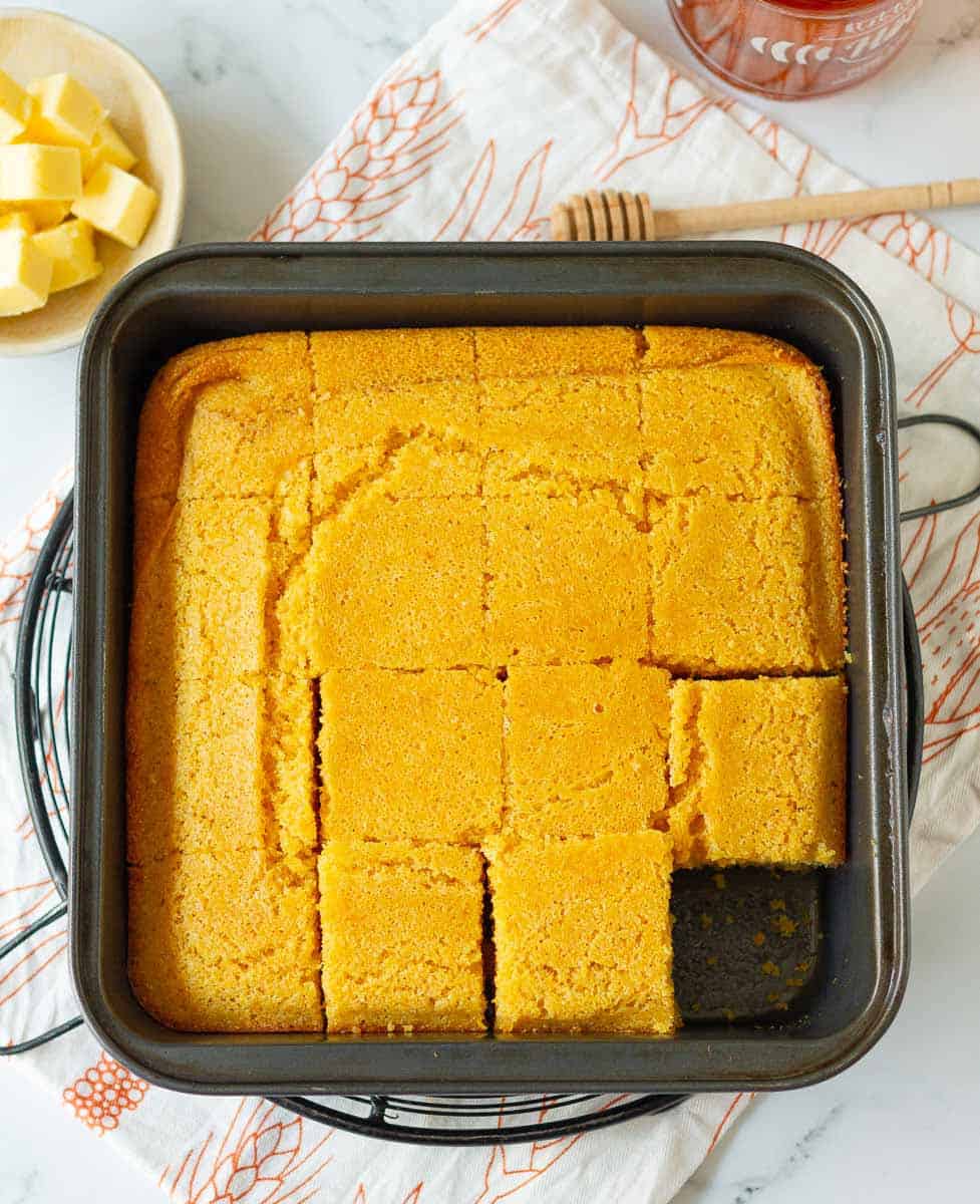 Homemade Cornbread cut into squares in a metal baking pan.