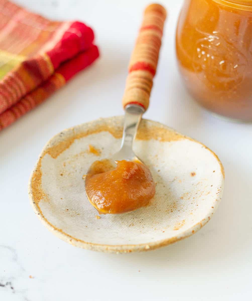 a spoonful of apple butter on a spoon to show its buttery texture.