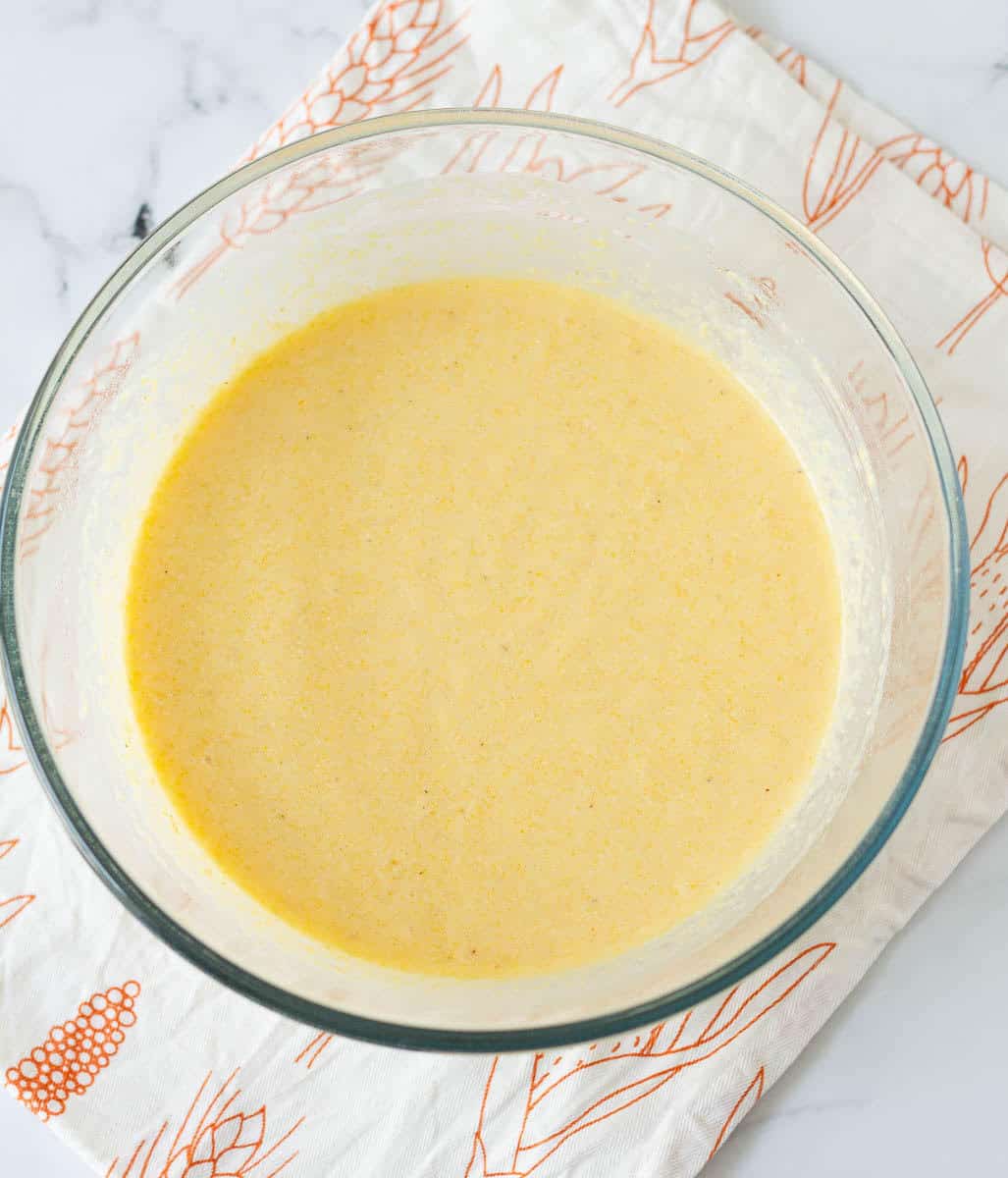 ready batter for homemade cornbread in a large glass bowl on a kitchen towel.