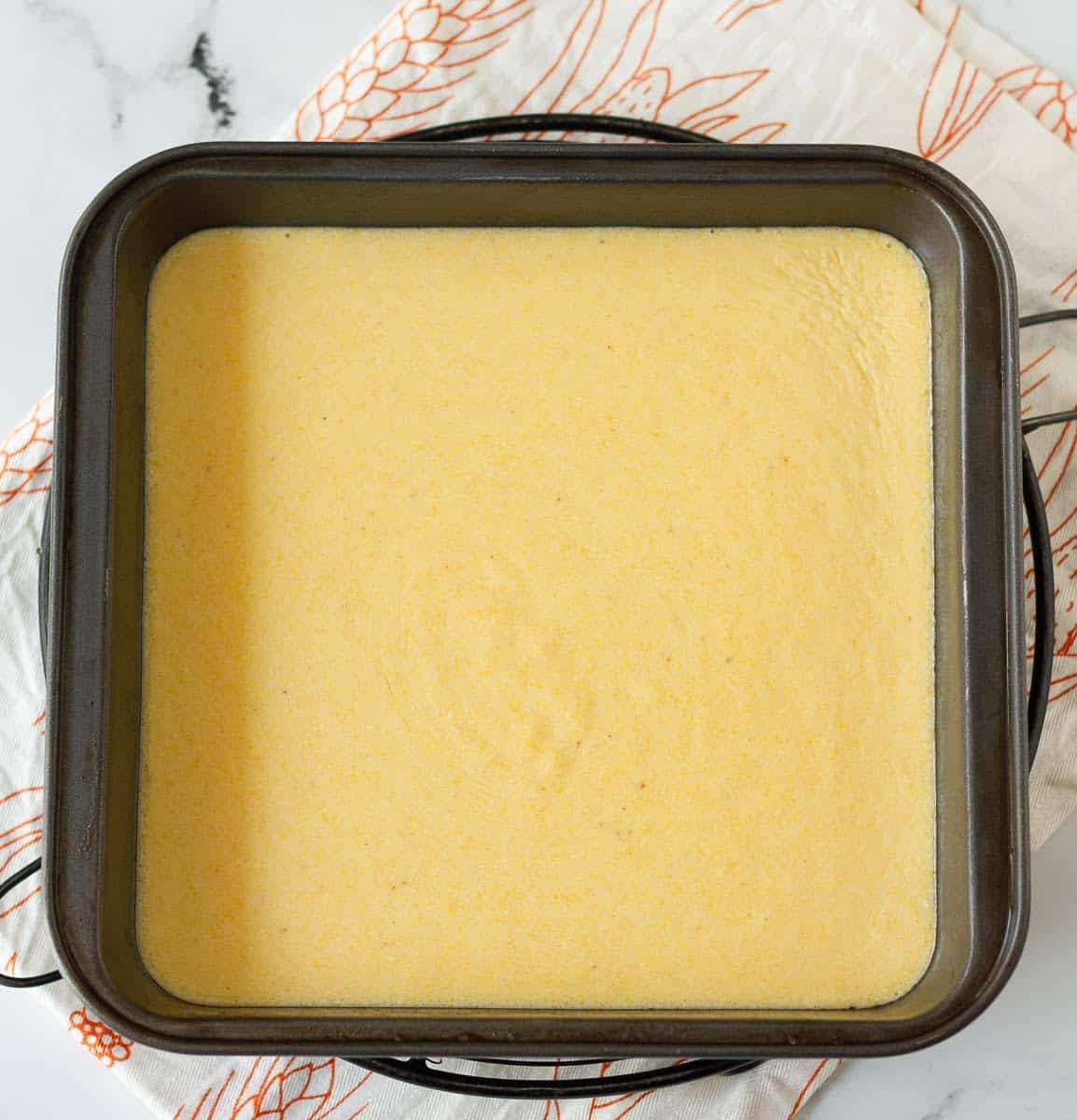 Cornbread batter in a hot square metal baking pan.