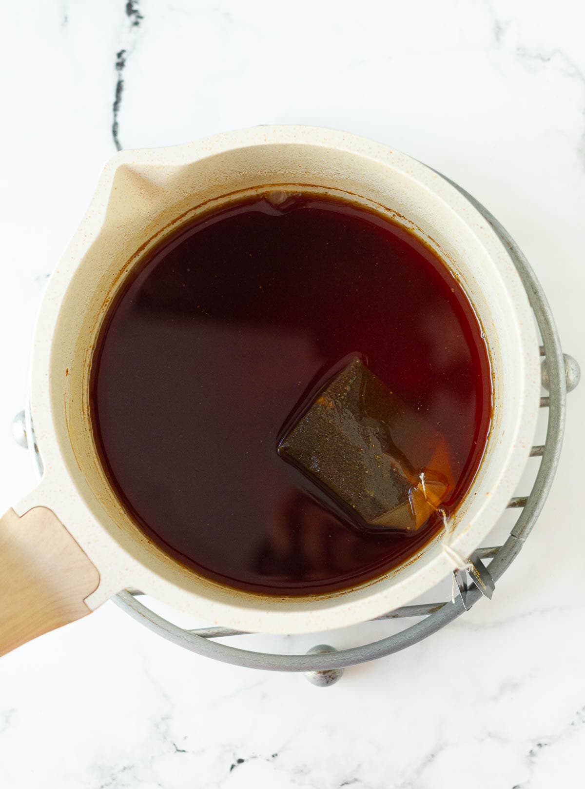Brewing black tea in a white saucepan.