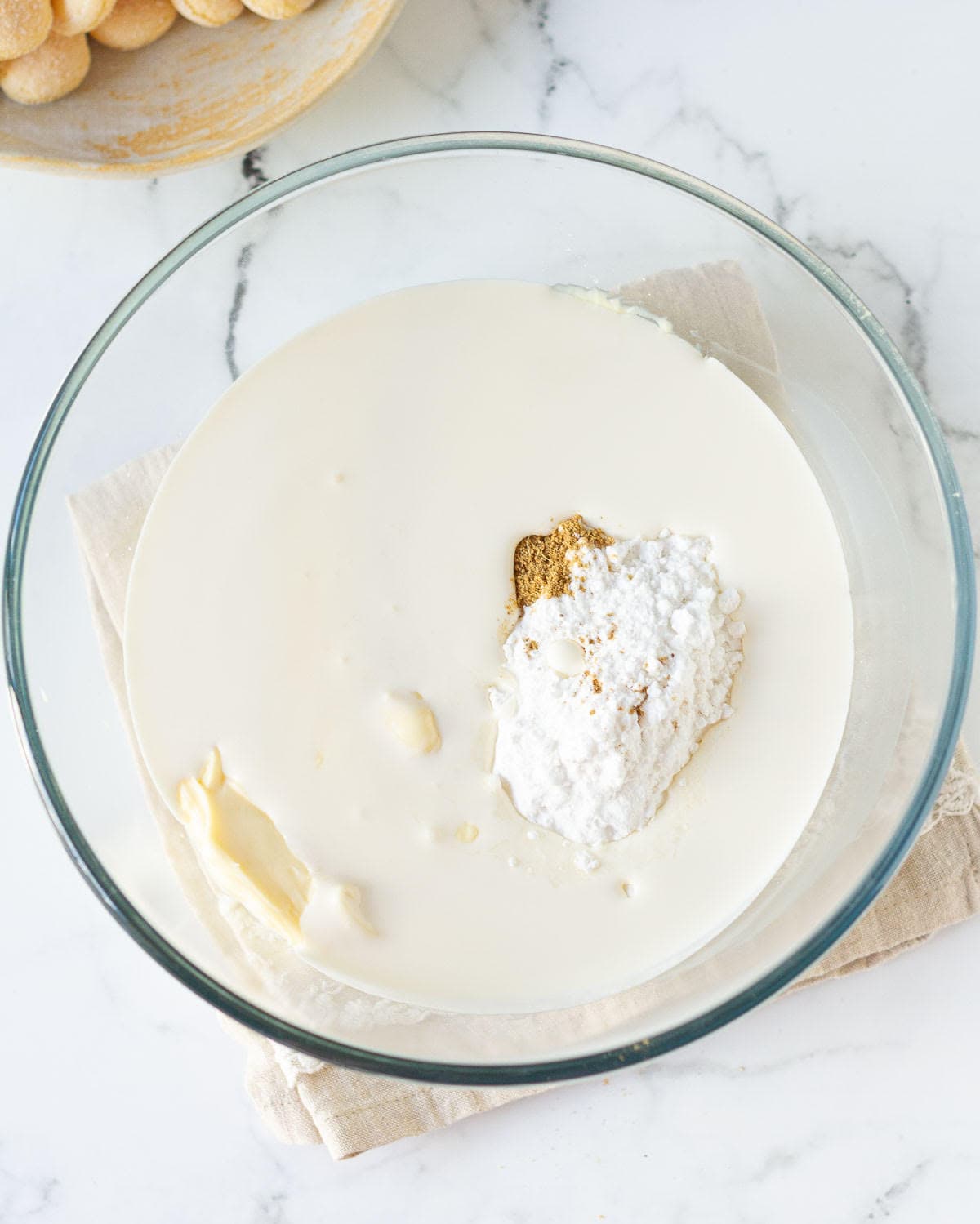 Mascarpone cheese,sugar,chai masala, and cream in a glass bowl.
