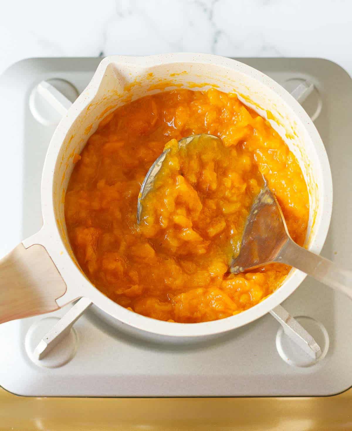 Mashing the cooked persimmons with a potato masher.