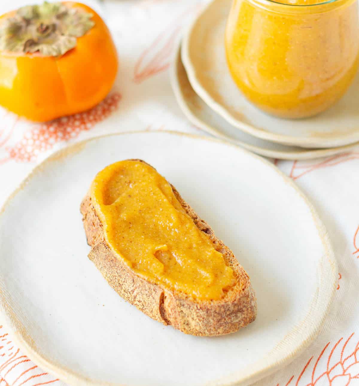 persimmon jam spread on a toast on a small plate.