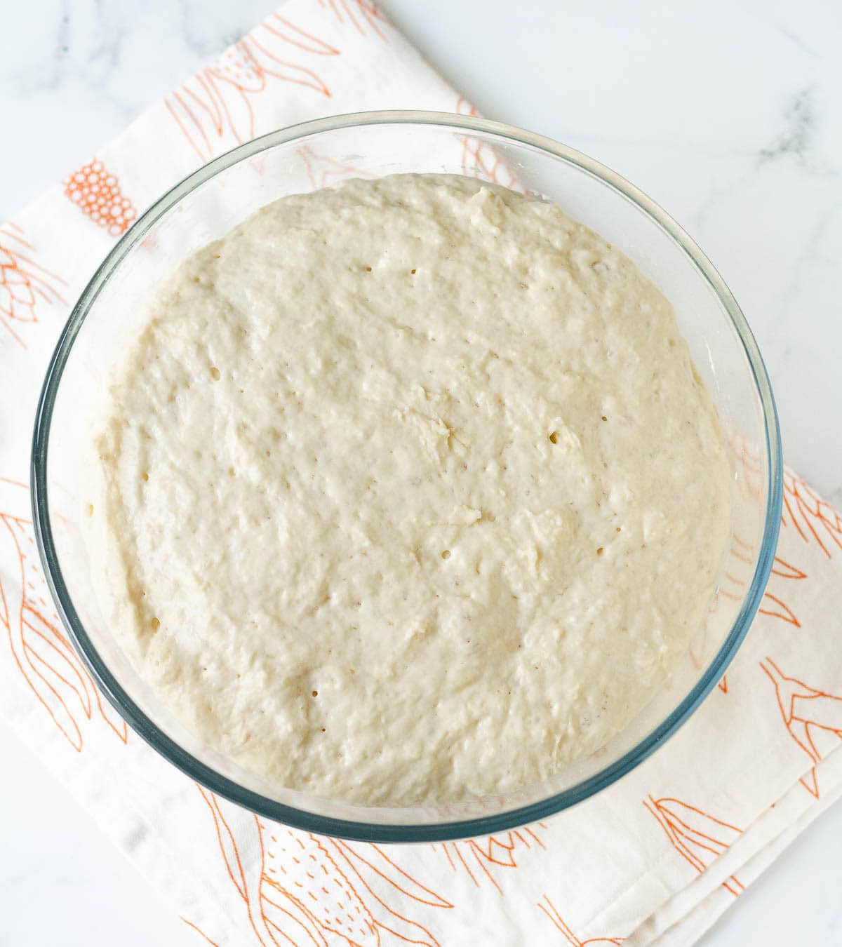 proofed no-knead bread dough in a glass mixing bowl.
