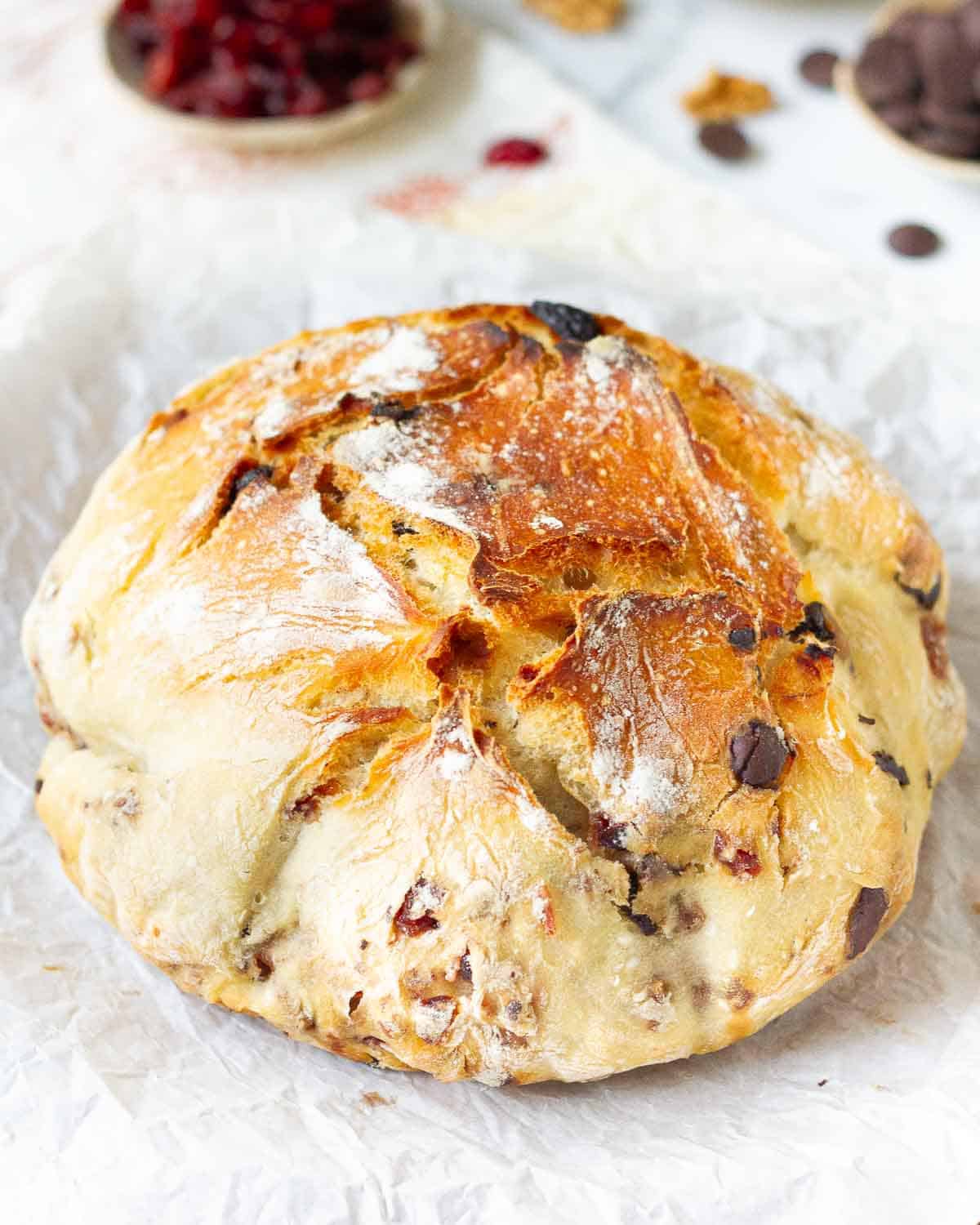 baked cranberry walnut bread loaf on parchment paper.