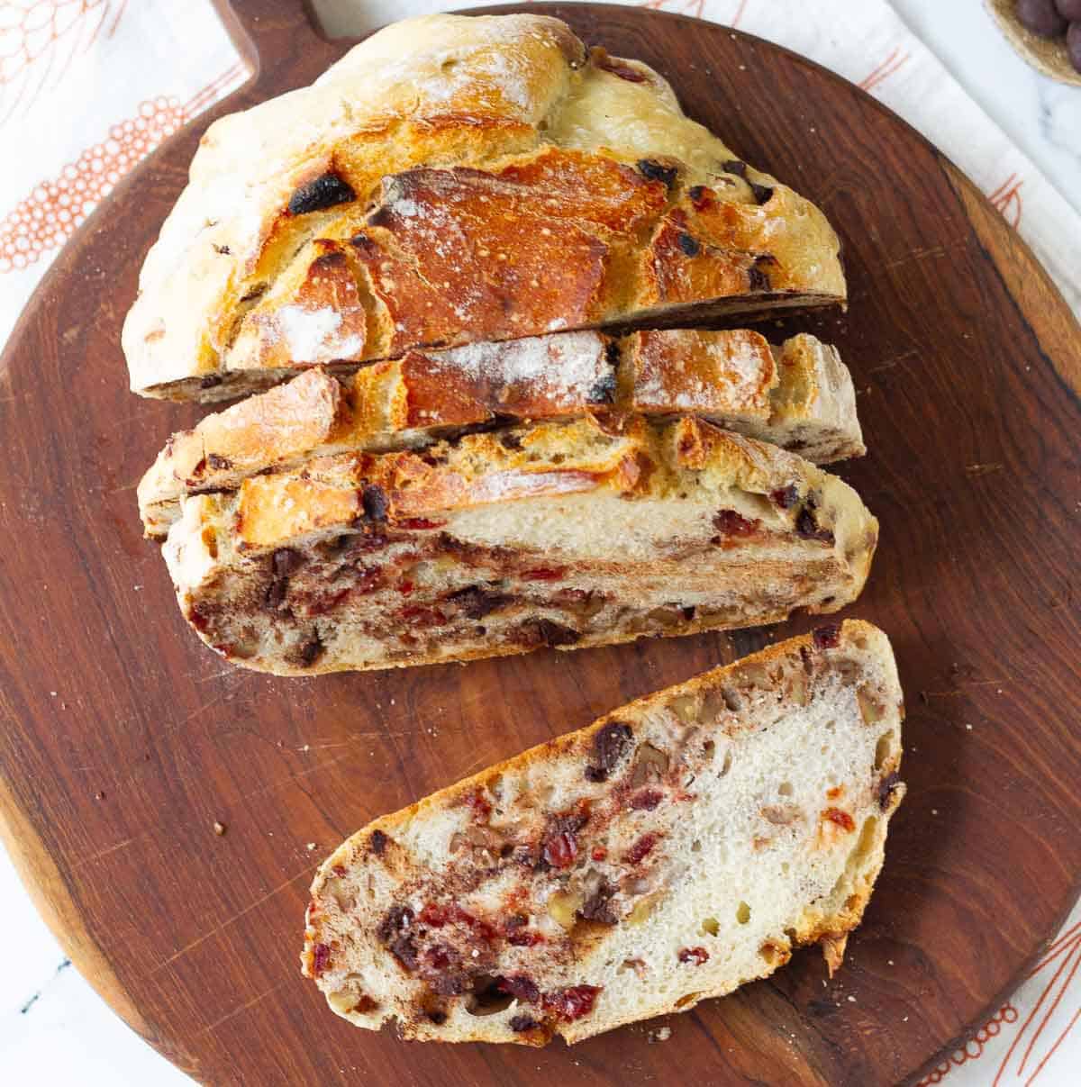 sliced cranberry chocolate bread on a wooden board.