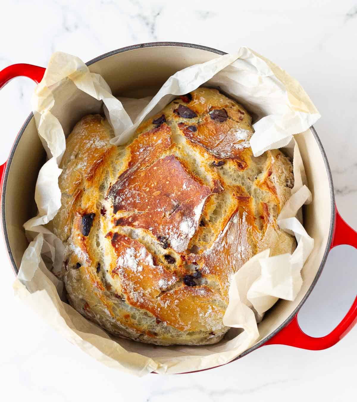 baked no-knead bread on a parchment paper in a Dutch oven.