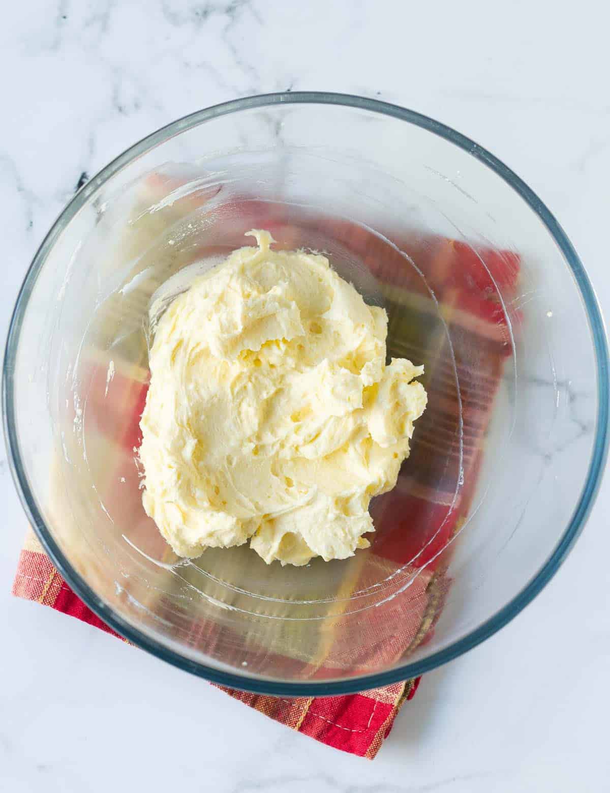 a fluffy mixture of butter and cream cheese in a glass mixing bowl.