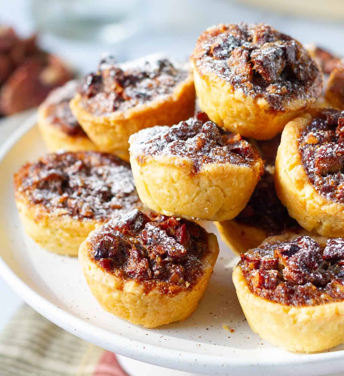 pecan tassies piled up on a cake stand.