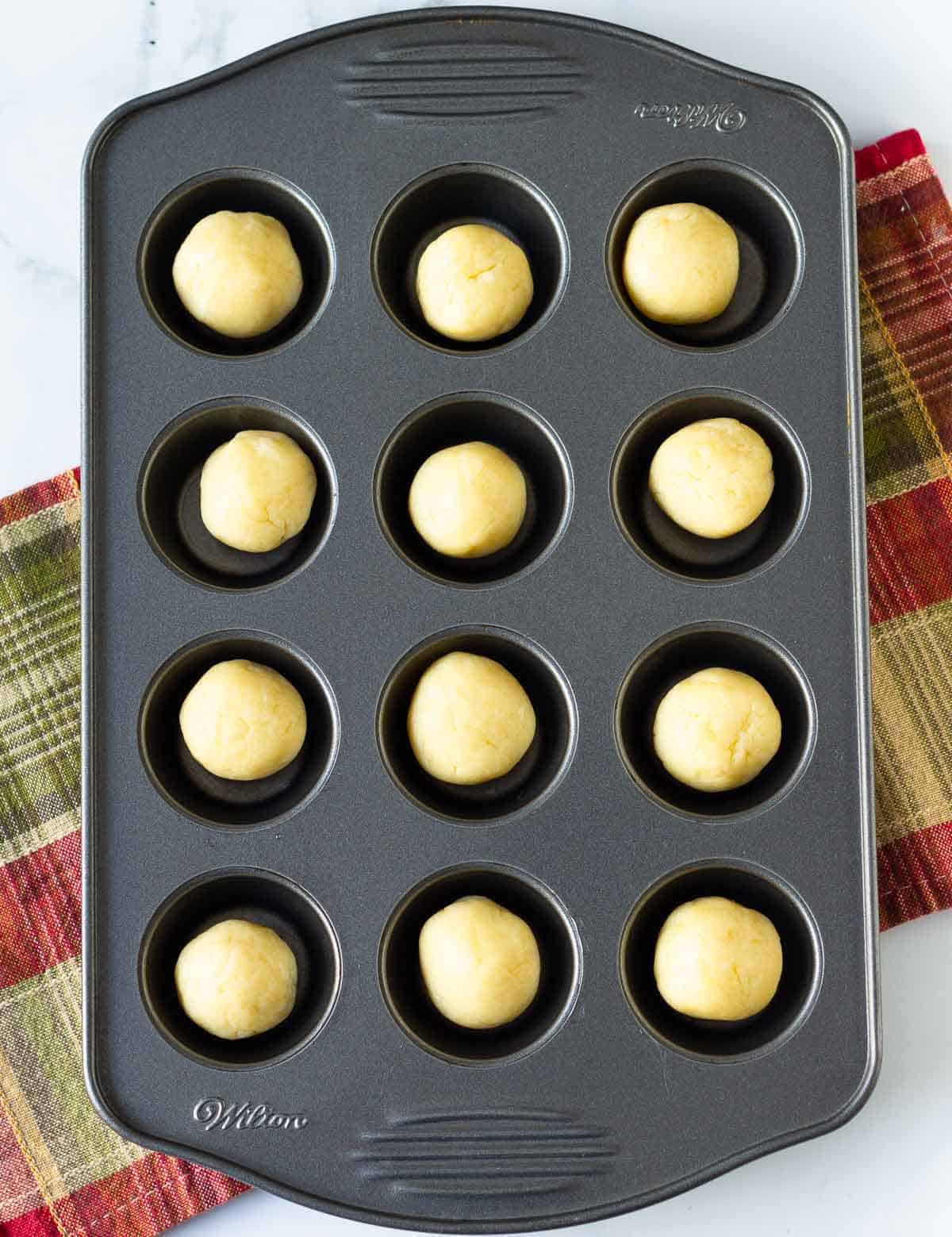 dough balls in a mini muffin pan.