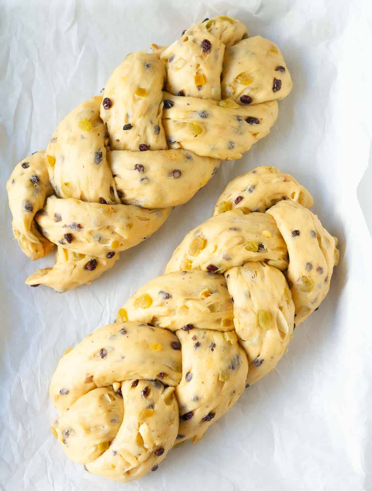 proofed braided bread loaves on parchment paper.