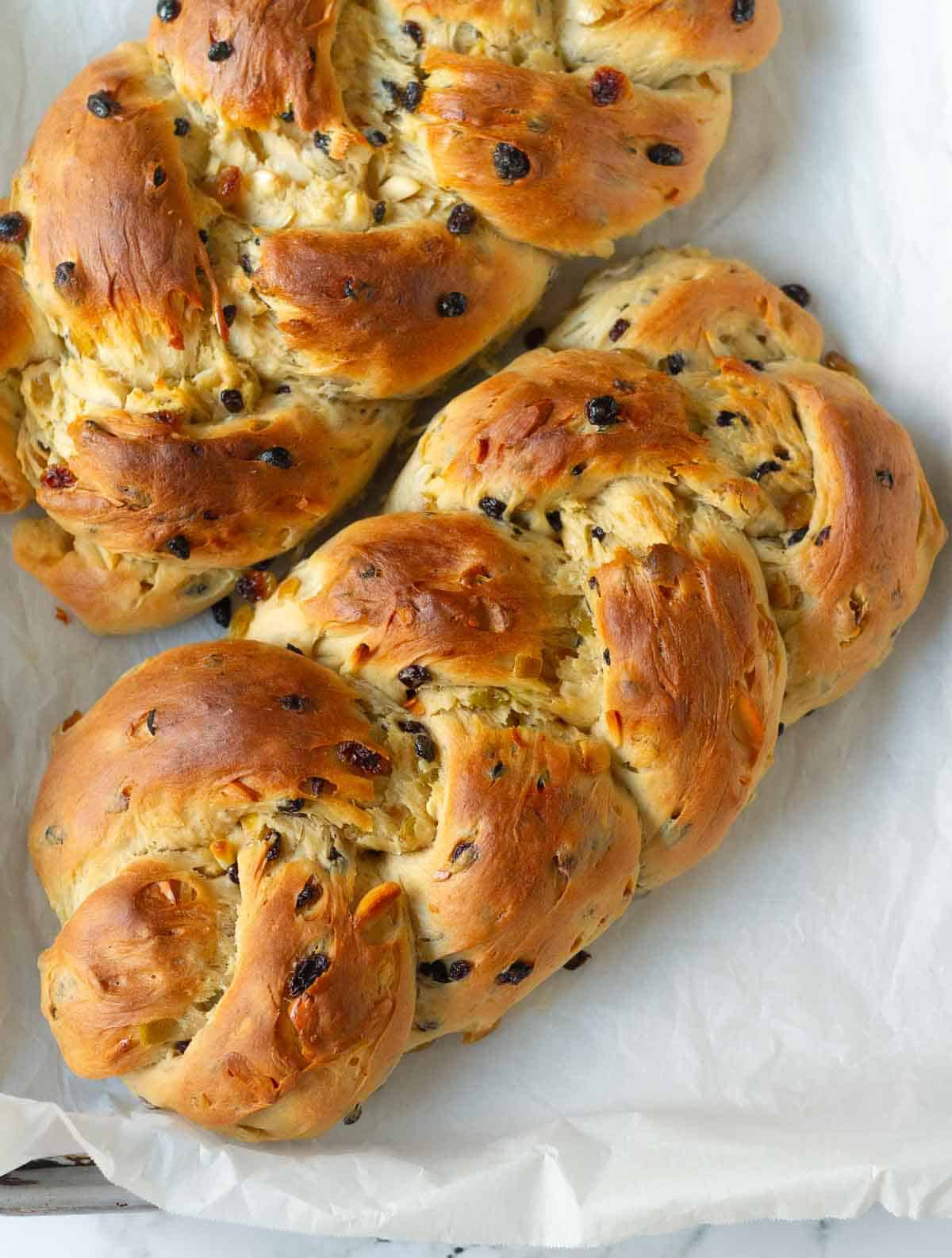 two braided baked bread loaves on parchment paper.