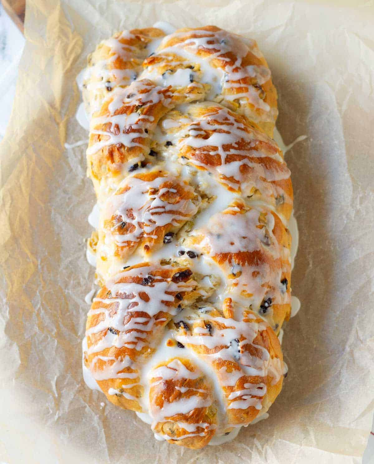 stollen bread with white glaze on parchment paper.