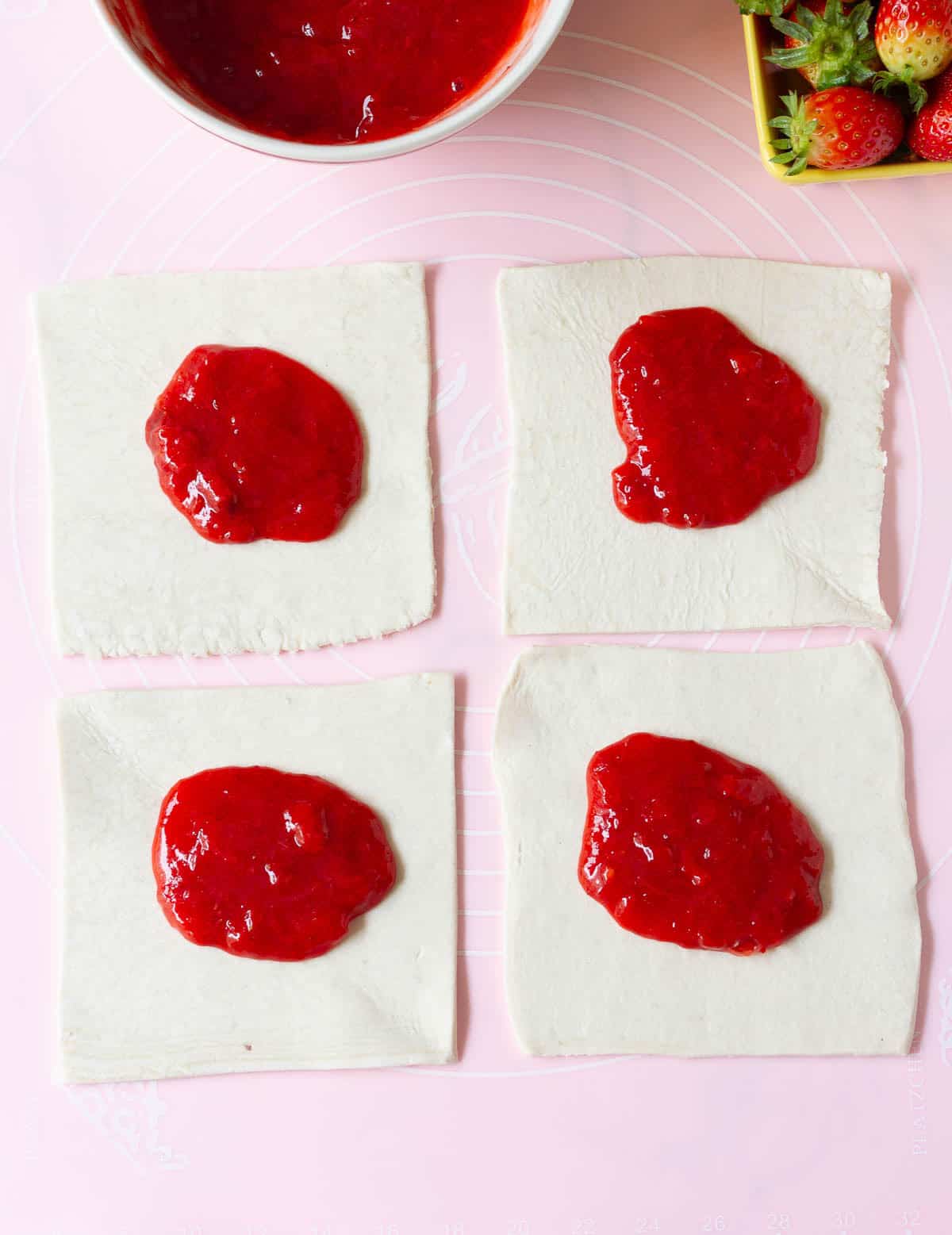 strawberry filling in the center of 4 squares of puff pastry.