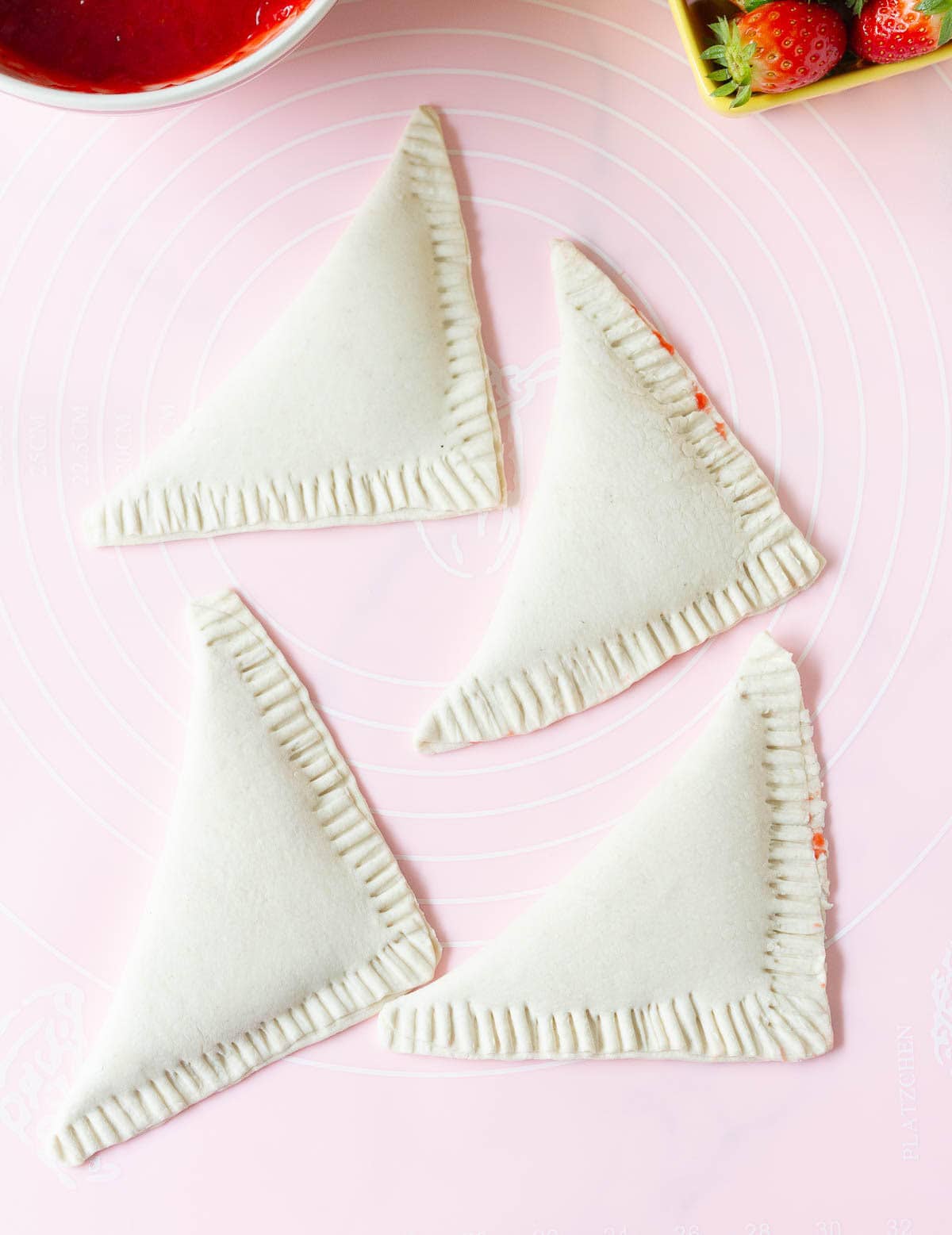 Four folded over puff pastry squares with crimped edges.