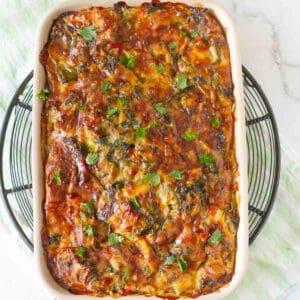 breakfast casserole with eggs and veggies in a baking dish on a metal trivet.