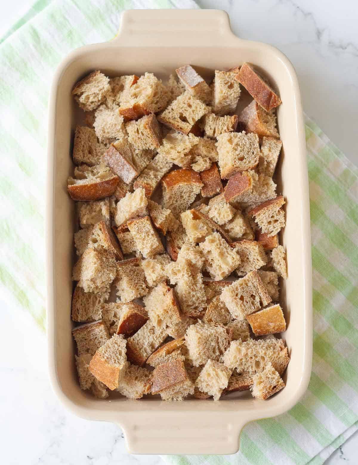 a layer of cubed sourdough bread in a casserole dish.