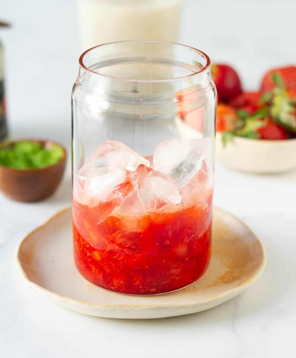 chopped strawberries topped with ice in a glass.