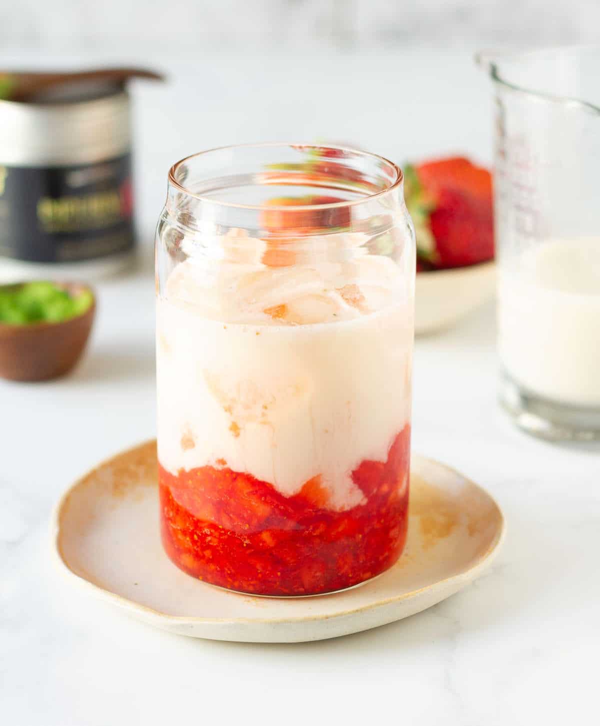 Almond milk on top of ice and chopped strawberries in a glass.
