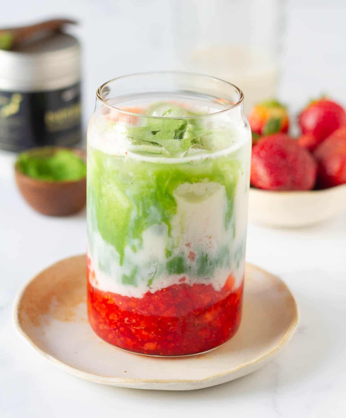 Matcha mixture on top of milk and strawberries in a glass.