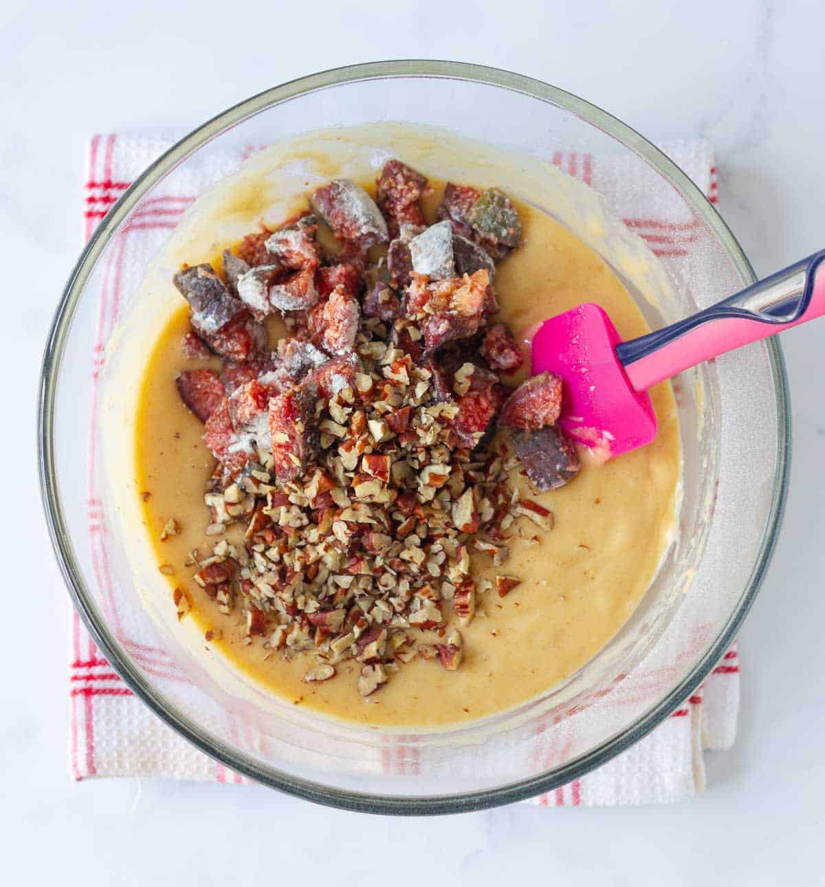 Chopped figs and pecan on top the bread batter with a silicone spatula.
